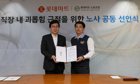 문영표 대표(왼쪽)와 최석주 노조 위원장이 직장 내 괴롭힘 근절을 위한 노사 공동 선언서에 서명을 하고 기념촬영을 하고 있다. <롯데마트 제공>